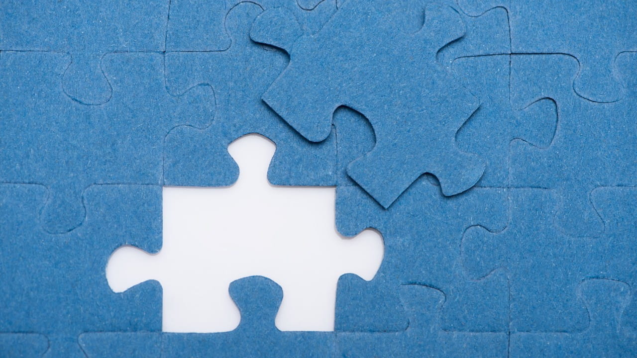 Tfr: tutto quello che devi saperePrimo piano di un puzzle blu con un pezzo mancante e posizionato adiacente al suo posto. I pezzi del puzzle si incastrano, con lo sfondo bianco visibile attraverso lo spazio.
