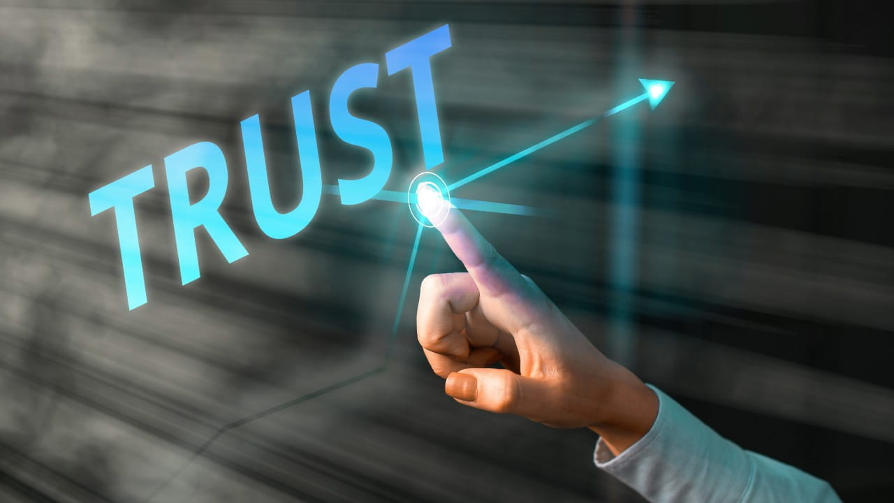 Immagine con un dito che punta sulla parola trust, scritta in azzurro