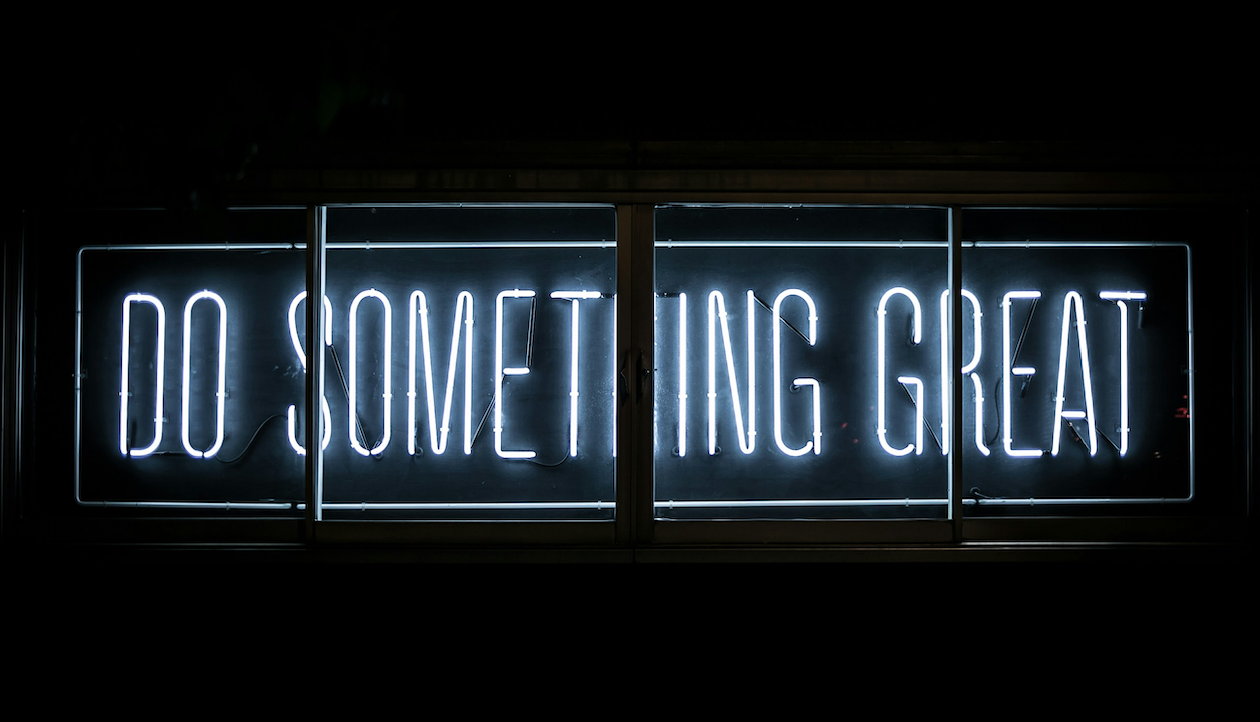 Un'insegna al neon con lettere bianche su sfondo nero recita "FAI QUALCOSA DI GRANDE", anche se la lettera "H" di "SOMETHING" è spenta e mancante: una metafora calzante per l'imprevedibile percorso di creazione di una startup.