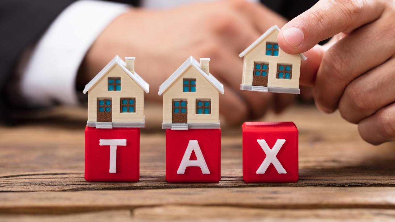 Immagine con casette di legno e con dei cubi che formano la parola tax, per simboleggiare il cambio e trasferimento di residenza.