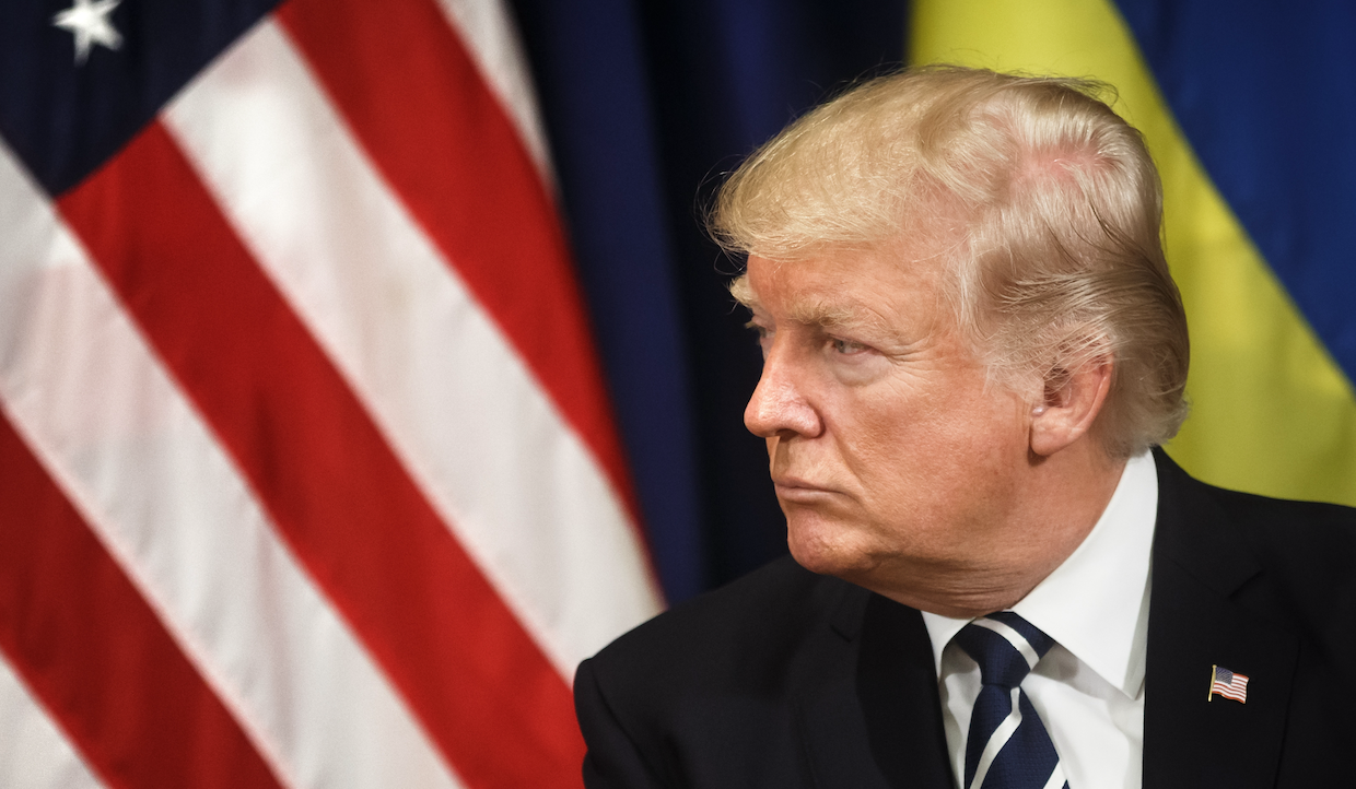 Un uomo in giacca e cravatta guarda verso destra, incarnando la sostenibilità. Dietro di lui ci sono parti delle bandiere americana e ucraina, che simboleggiano unità e responsabilità globale.