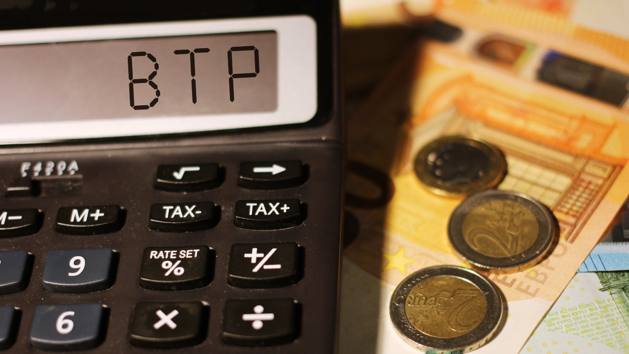 Monete e banconote sono sparse in giro, mentre una calcolatrice mostra la scritta "BTP" sullo schermo. Immagine btp-sicurezza-trappola-investimenti collegata all'articolo "Btp: sicurezza o trappola? Come proteggere gli investimenti"