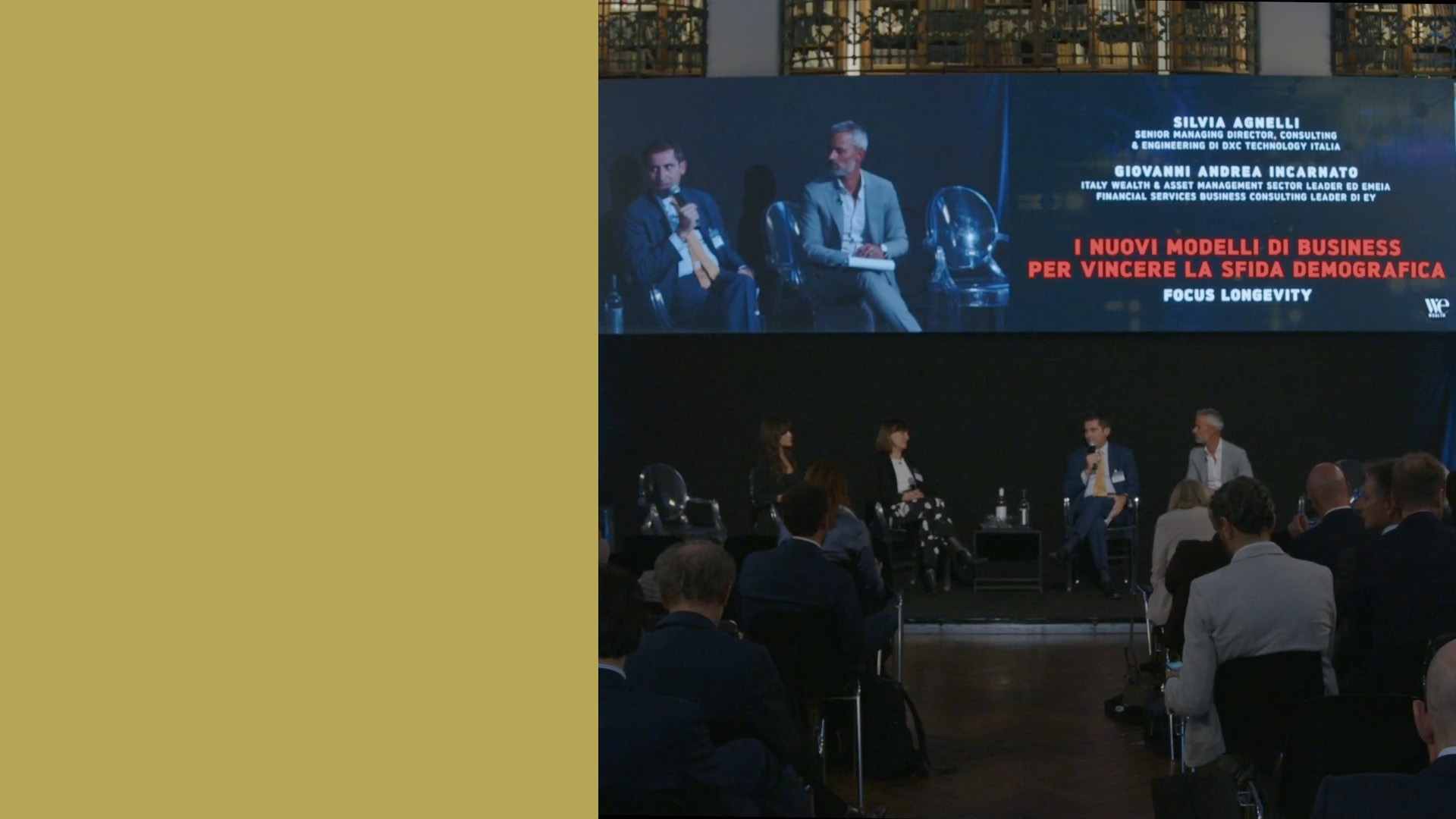 Tavola rotonda su "I Nuovi Modelli di Business per Vincere la Sfida Demografica" con tre relatori sul palco e un pubblico. Un grande schermo sullo sfondo mostra il titolo e i nomi dei relatori.