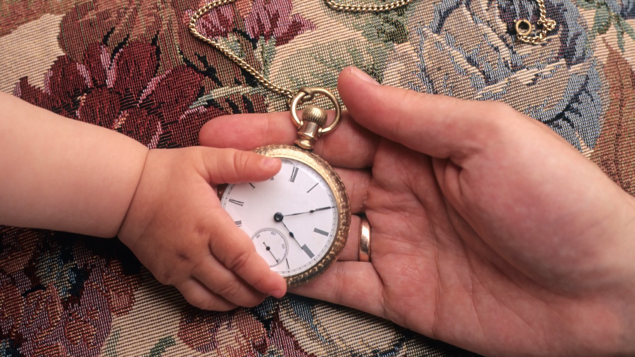 La mano di un bambino tocca un orologio da tasca d'oro tenuto dalla mano di un adulto, a simboleggiare il legame senza tempo di impresa familiare in vista del passaggio generazionale. impresa-familiare-regole-passaggio-generazionale-vincente
