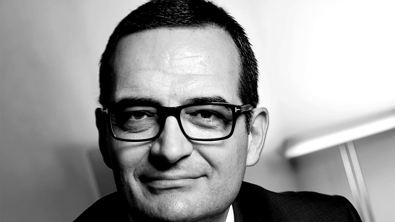 In foto, Alessandro Vagnucci, deputy head of Mediobanca Private Banking, ritratto in bianco e nero, sorridente, guarda la telecamera su uno sfondo sfocato uniforme.