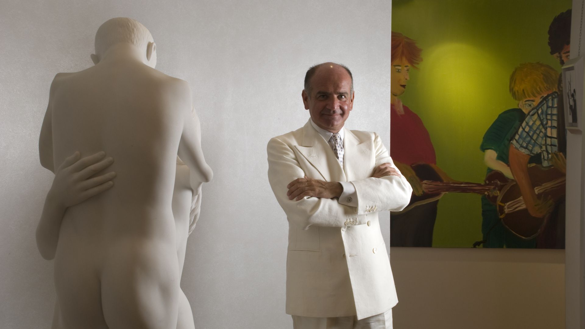 Un uomo in abito bianco in piedi accanto a una statua.