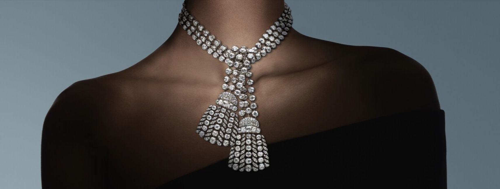 Una persona che indossa un'elegante collana di diamanti di Maria Antonietta con due elaborate nappe, su uno sfondo scuro. La collana presenta più fili di pietre scintillanti, oltre ai gioielli dello zar di Bulgaria