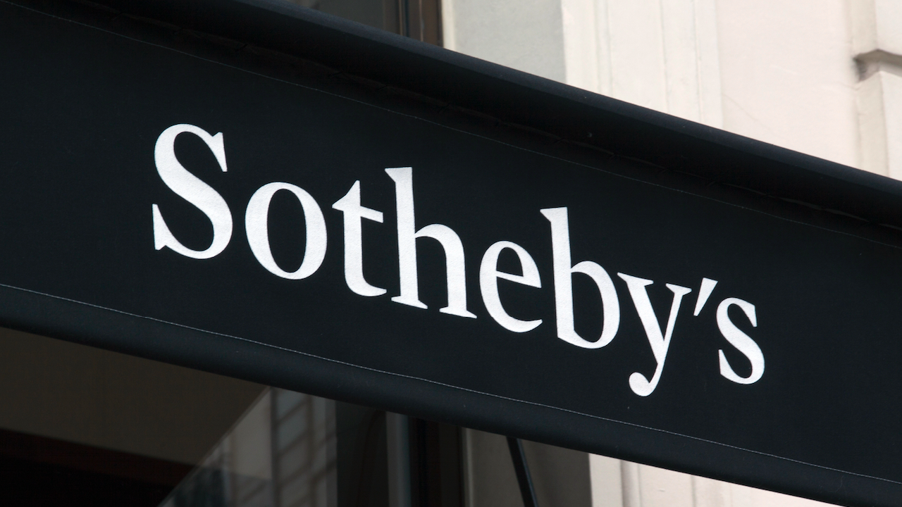 L'immagine mostra il logo "Sotheby's" in testo bianco su sfondo nero, esposto su un cartello all'esterno di un edificio.