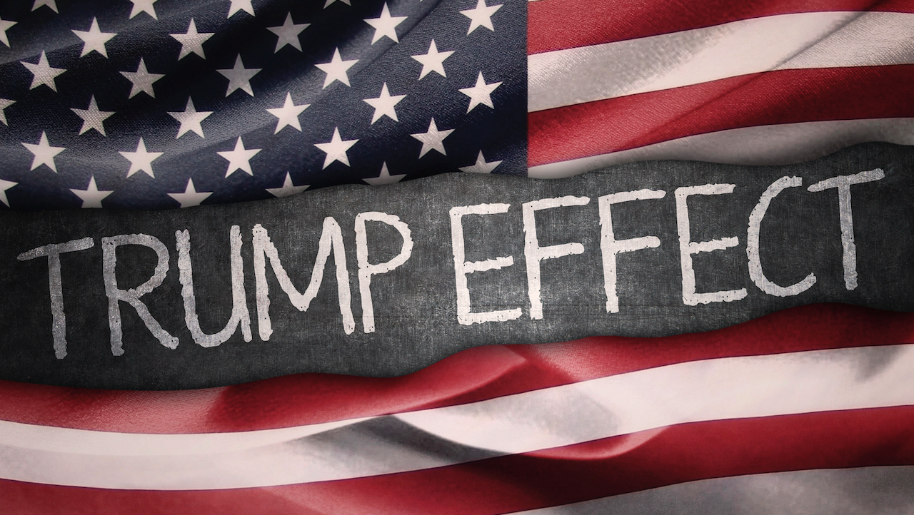 Una bandiera americana fa da sfondo al testo "TRUMP EFFECT", scritto in grassetto e bianco al centro.