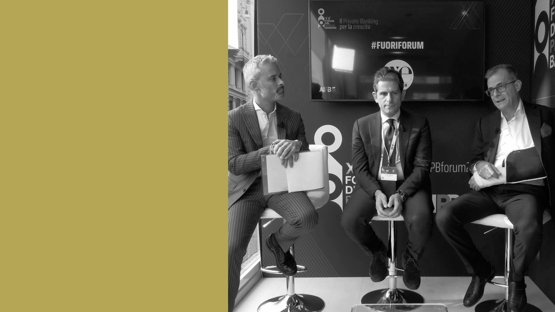 Piemilio Gadda, Canino Bonaventura e Lorenzo Palleroni in giacca e cravatta sono seduti su degli sgabelli, impegnati in una discussione al forum di AIPB. Dietro di loro c'è uno schermo che mostra il nome dell'evento. L'ambiente sembra formale, con un focus su argomenti finanziari.