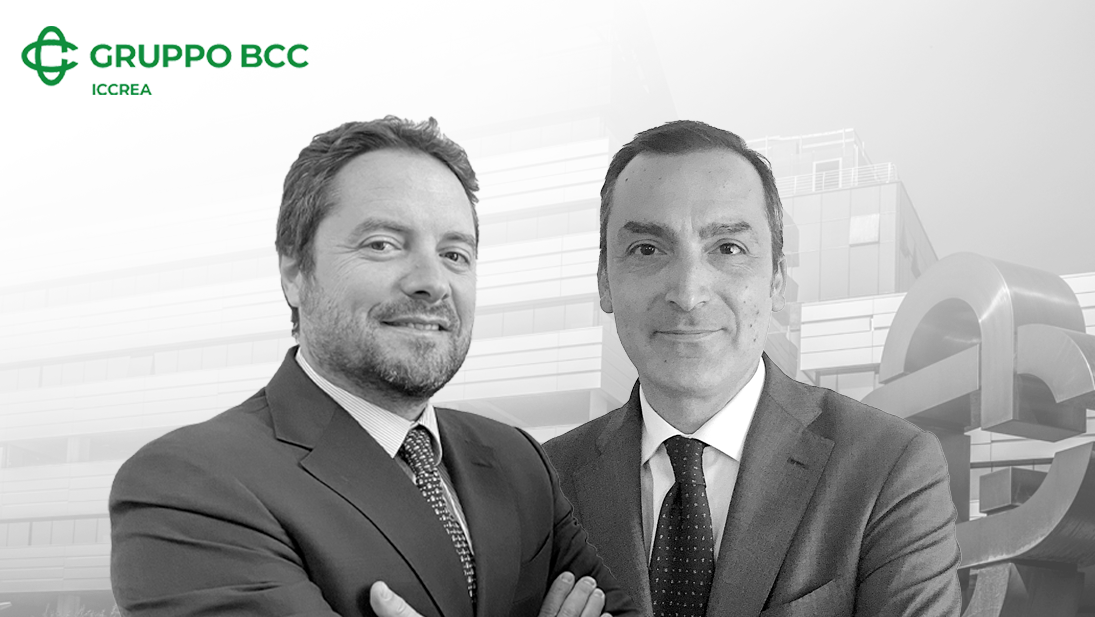 Due uomini in giacca e cravatta sono in piedi insieme, sorridenti, di fronte a un edificio moderno. Lo sfondo è in scala di grigi, con il logo "GRUPPO BCC ICCREA" nell'angolo in alto a sinistra.