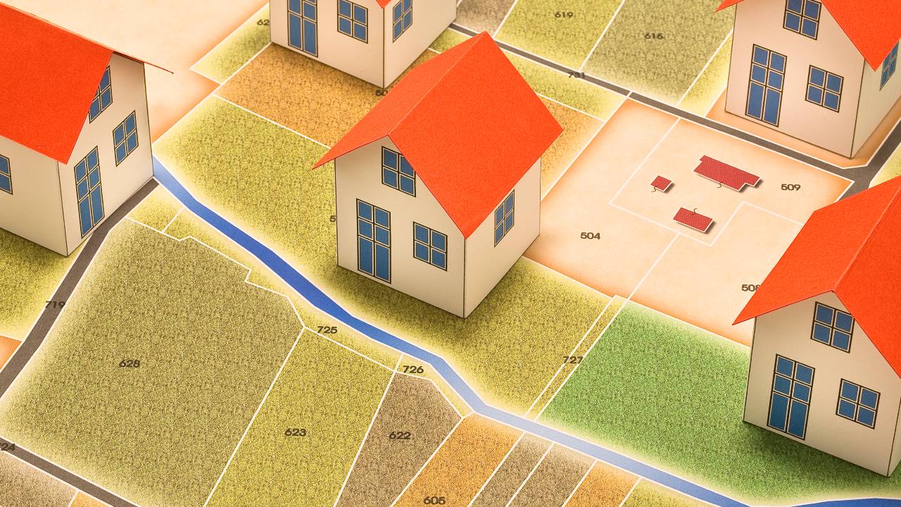 Mappa di un'area con case a tetti rossi, lotti numerati, sentieri tortuosi e un corso d'acqua. Le case sono state utilizzate per riprendere il concetto di residenza fiscale.