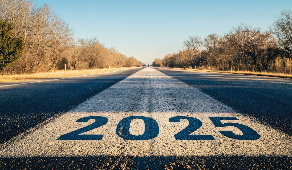 Una mano capovolge un blocco di legno che mostra il numero 4 al numero 5, accanto ai blocchi che mostrano 202. La scena simboleggia la transizione dall'anno 2024 al 2025 su uno sfondo neutro.