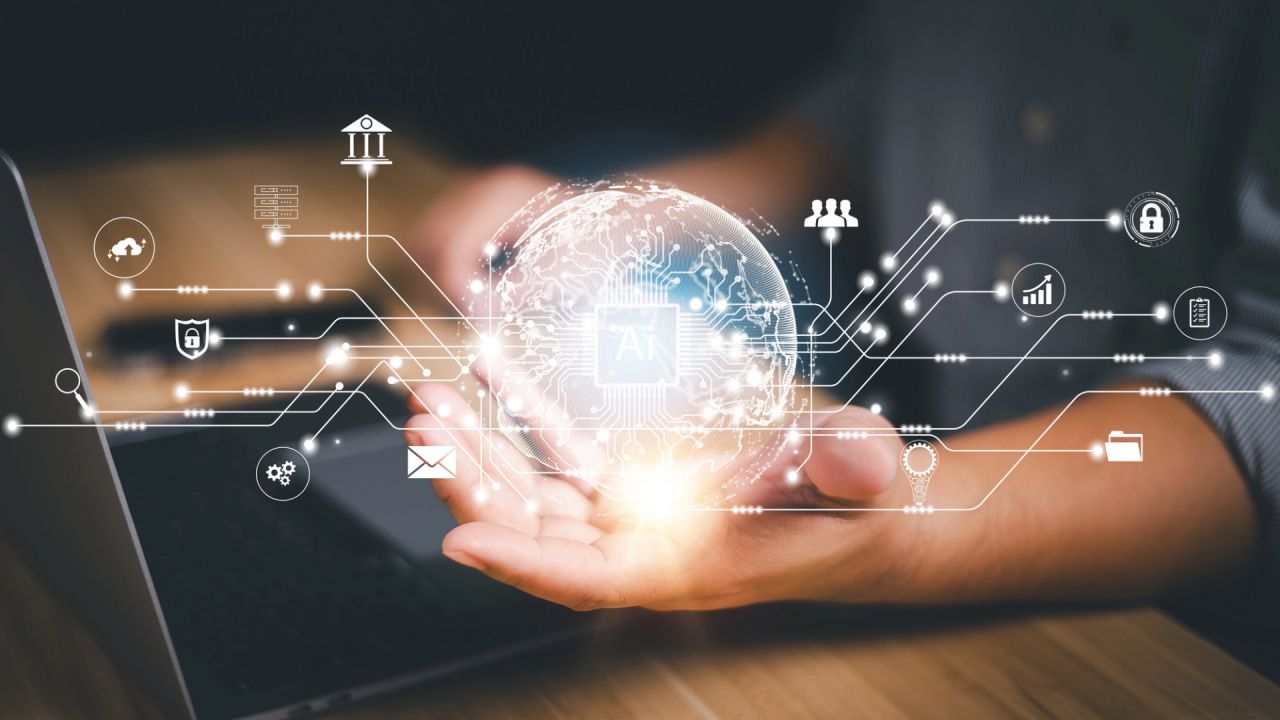 Una persona tiene in mano una sfera digitale luminosa con icone interconnesse, che rappresentano varie tecnologie. Lo sfondo presenta un laptop, che simboleggia l'integrazione e l'avanzamento nell'intelligenza artificiale e nella tecnologia.