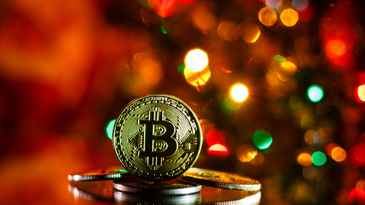 Un Bitcoin dorato brilla in cima a una pila di monete, sullo sfondo di luci colorate e sfocate che evocano un'atmosfera festosa.