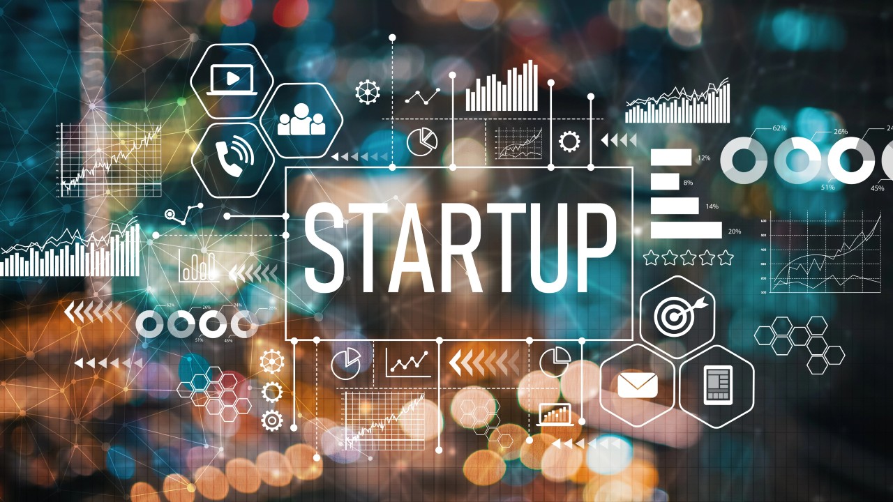 Un'immagine vibrante e astratta mostra la scritta "STARTUP" al centro, circondata da grafici digitali, icone e grafici che simboleggiano la tecnologia e la rapida crescita aziendale.