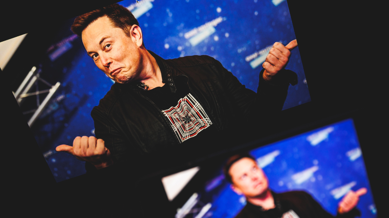 Una persona che fa un'espressione giocosa e punta il dito su uno sfondo blu con disegni astratti, che ricordano il comportamento eccentrico di Elon Musk. L'individuo indossa una giacca scura sopra una maglietta grafica, con un riflesso parziale o una sovrapposizione visibile sotto.