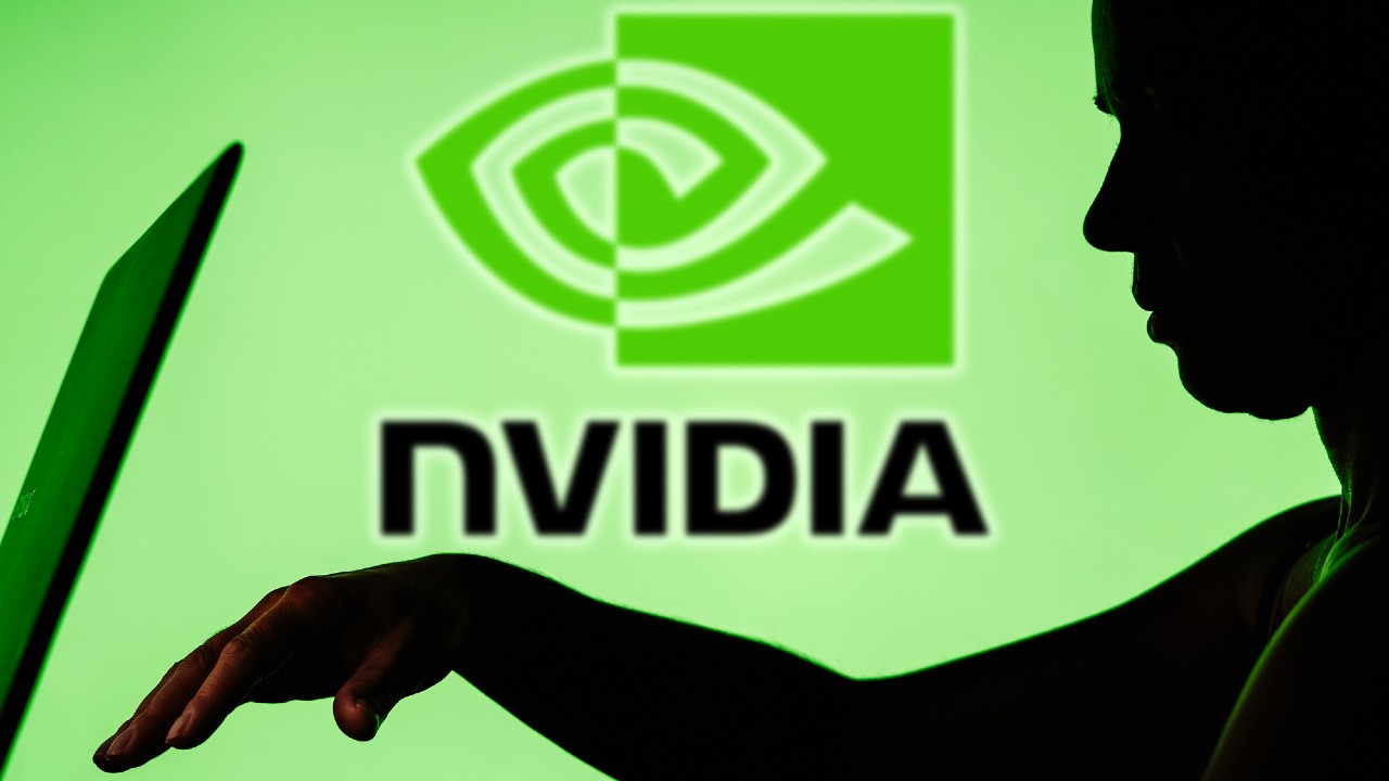 Silhouette di una persona che usa un laptop davanti a uno sfondo verde con il logo NVIDIA ben in vista. L'immagine suggerisce una connessione tra la tecnologia e l'azienda.