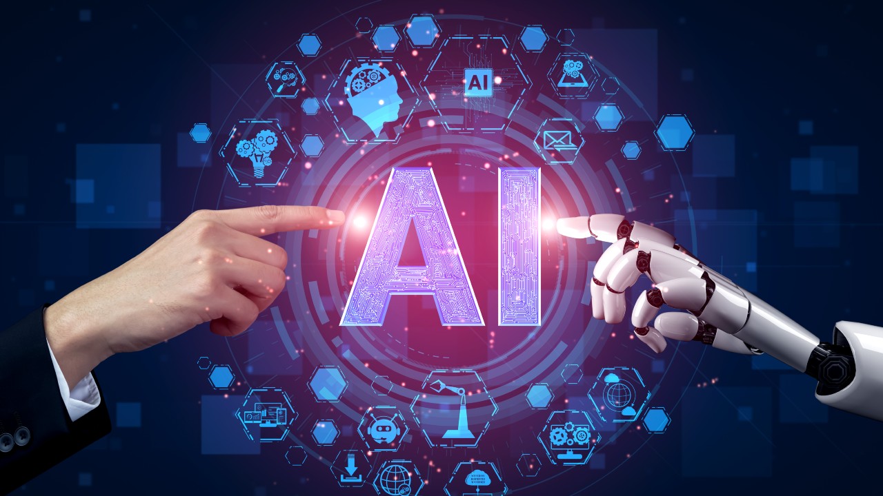 Una mano umana e una mano robotica puntano l'una verso l'altra verso la scritta "AI" di intelligenza artificiale scritta in grassetto tra di loro, circondata da varie icone tecnologiche.
