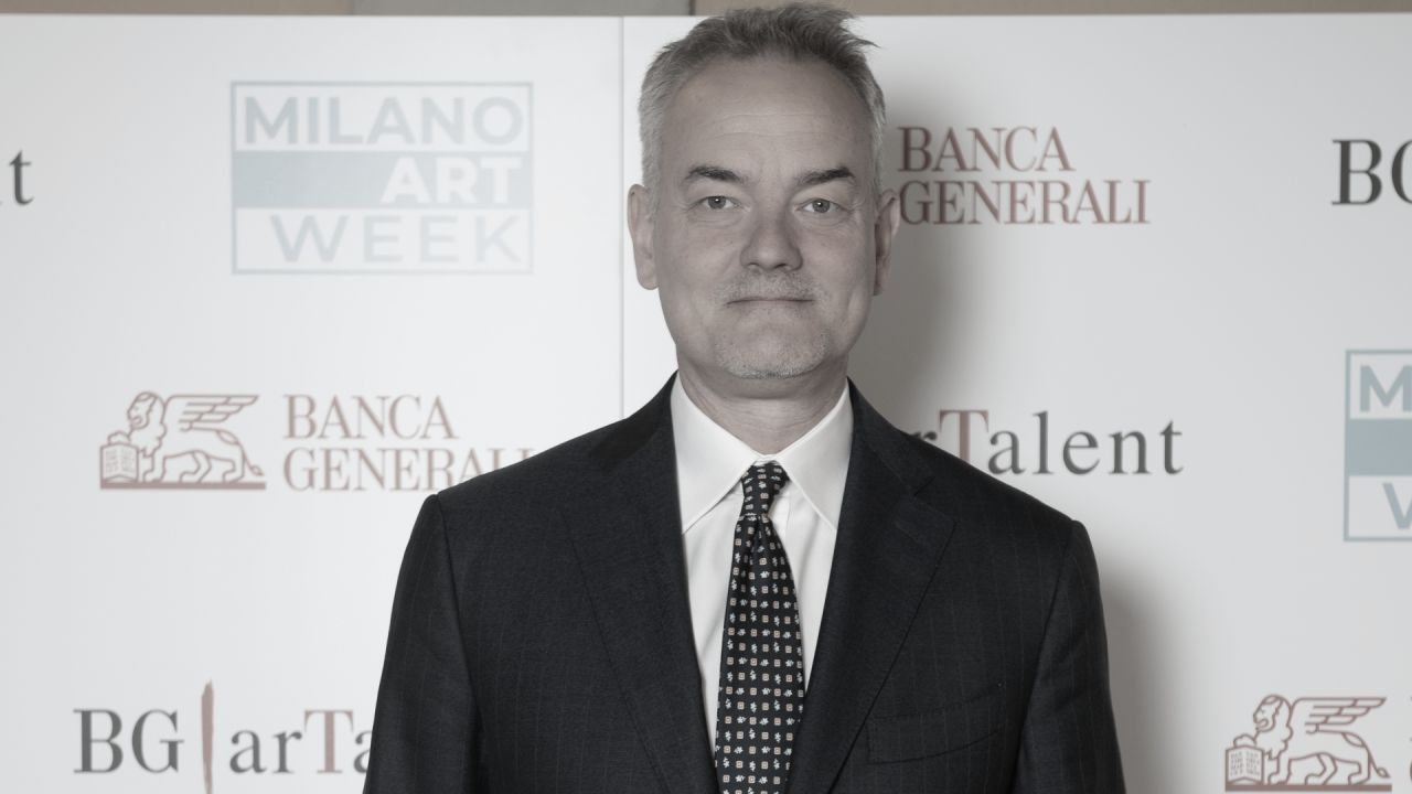 Un uomo in giacca e cravatta è in piedi su uno sfondo con i loghi della Milano Art Week, Banca Generali e BG Talent.