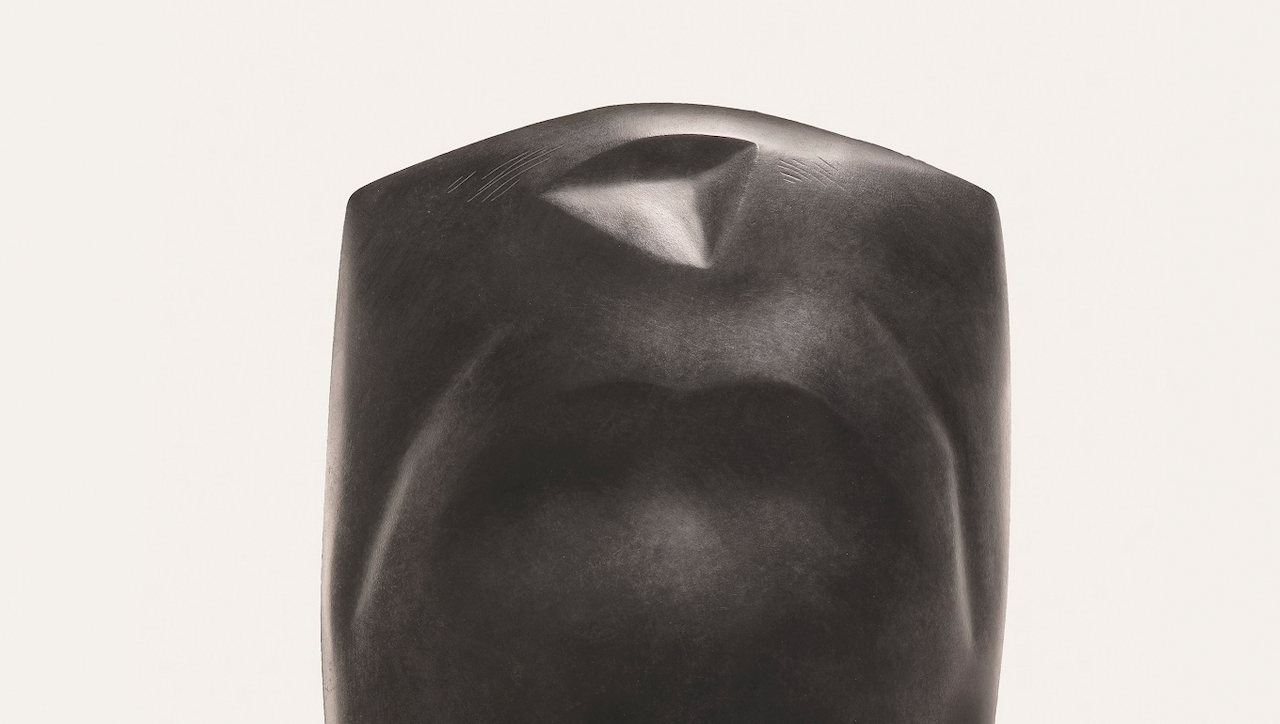 Una scultura astratta liscia e scura dal design minimalista, caratterizzata da curve delicate e una piega spigolosa e pronunciata nella parte superiore, su uno sfondo semplice.