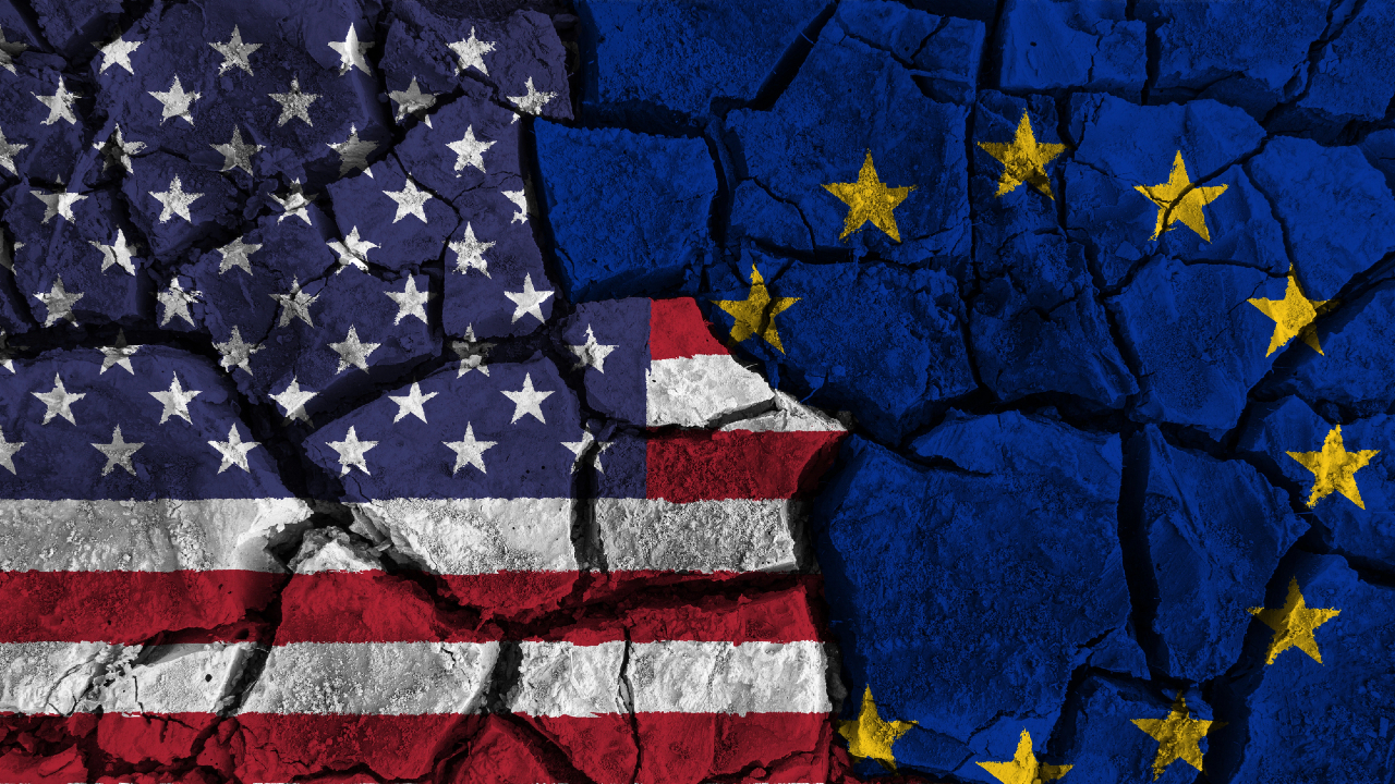 Il cemento crepato raffigura una spaccatura tra la bandiera degli Stati Uniti a sinistra e quella dell'Unione Europea a destra, a simboleggiare la divisione, mentre Wall Street trema per il crescente abisso.