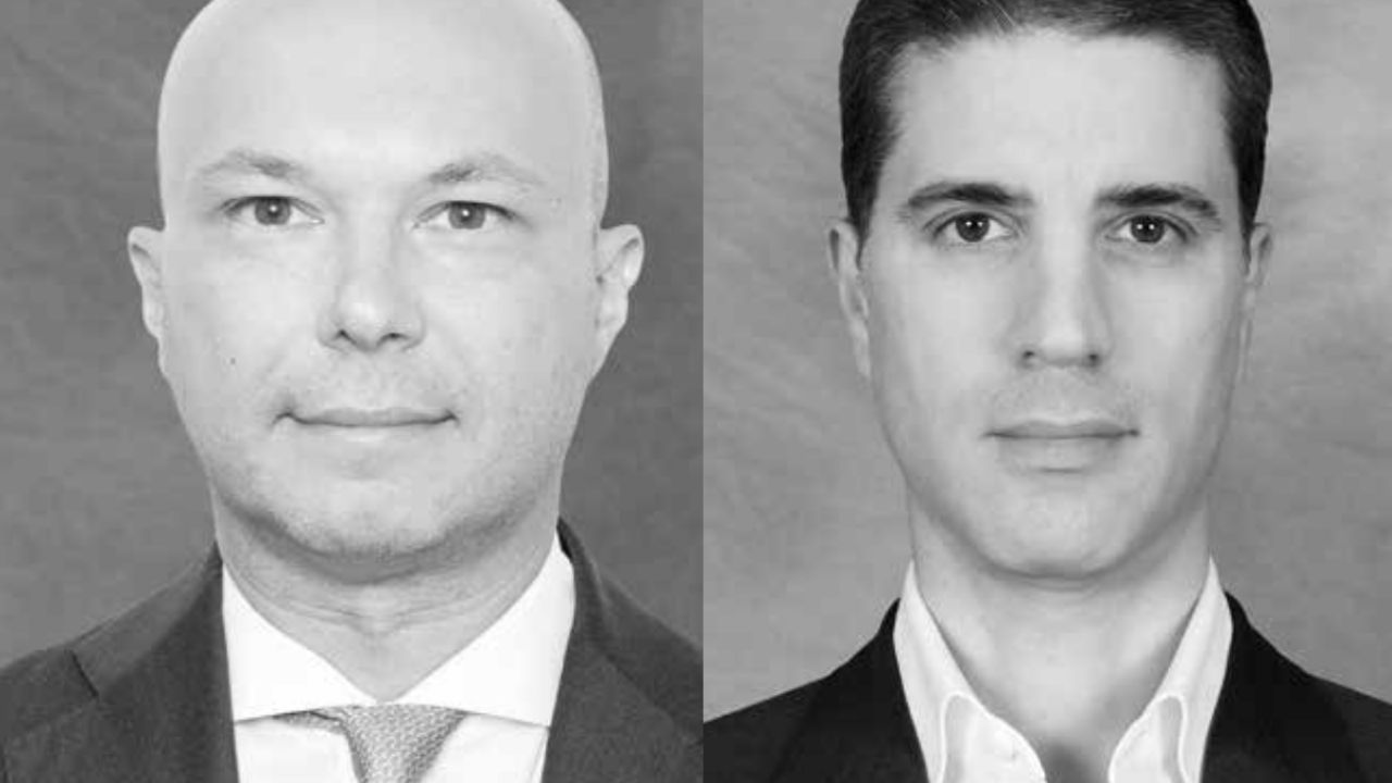 Due uomini in giacca e cravatta sono ritratti fianco a fianco in un ritratto in bianco e nero, evocando la raffinatezza della ricchezza privata di Blackstone. L'uomo calvo a sinistra e quello con i capelli scuri e ben pettinati guardano entrambi direttamente in camera con espressioni neutre.