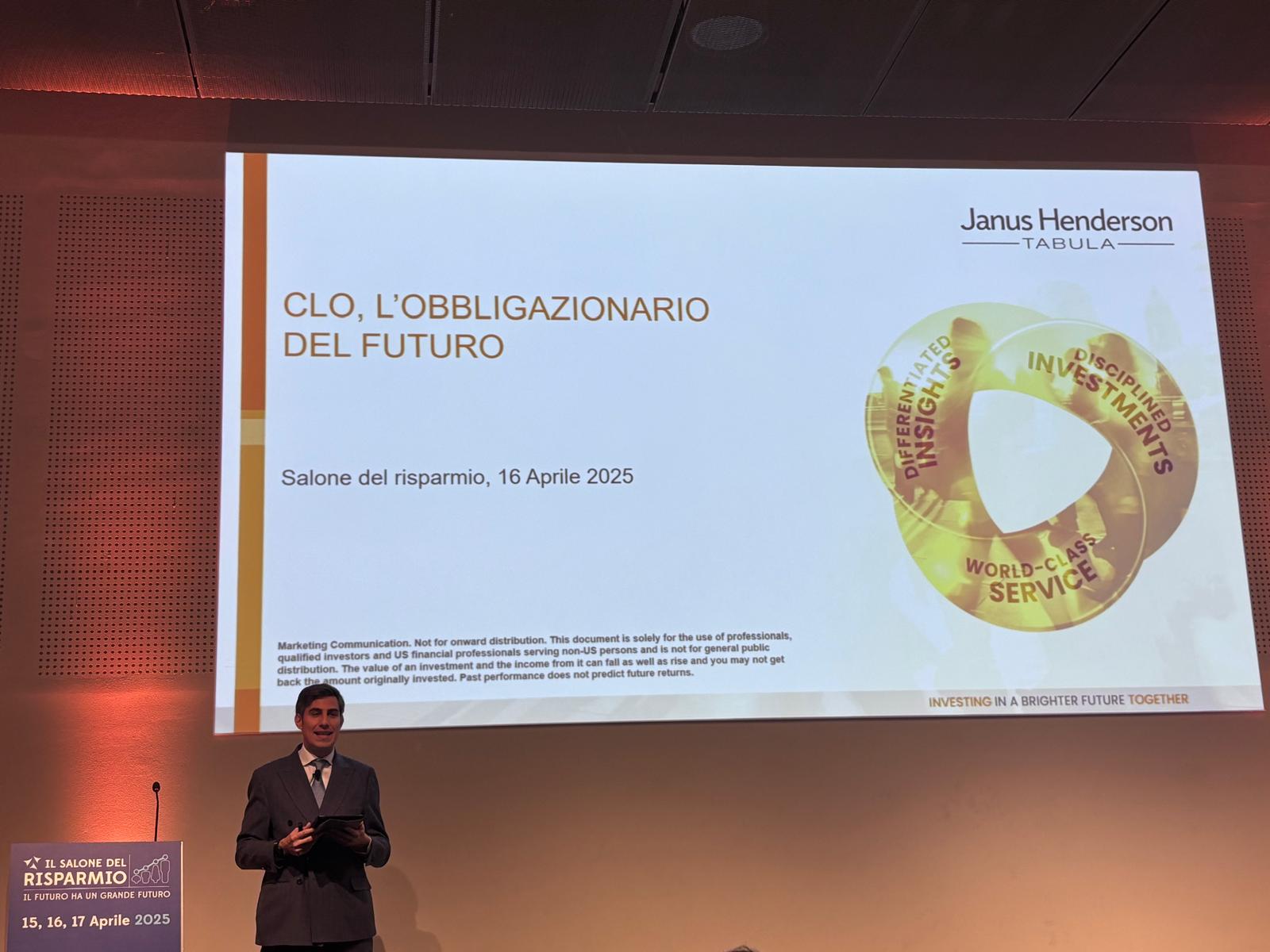 Un uomo in giacca e cravatta è in piedi sul palco accanto a un grande schermo che mostra una presentazione su CLO, intitolata "CLO, L'obbligatorio del futuro", per un evento del 16 aprile 2025, con loghi e un diagramma circolare di investimento.