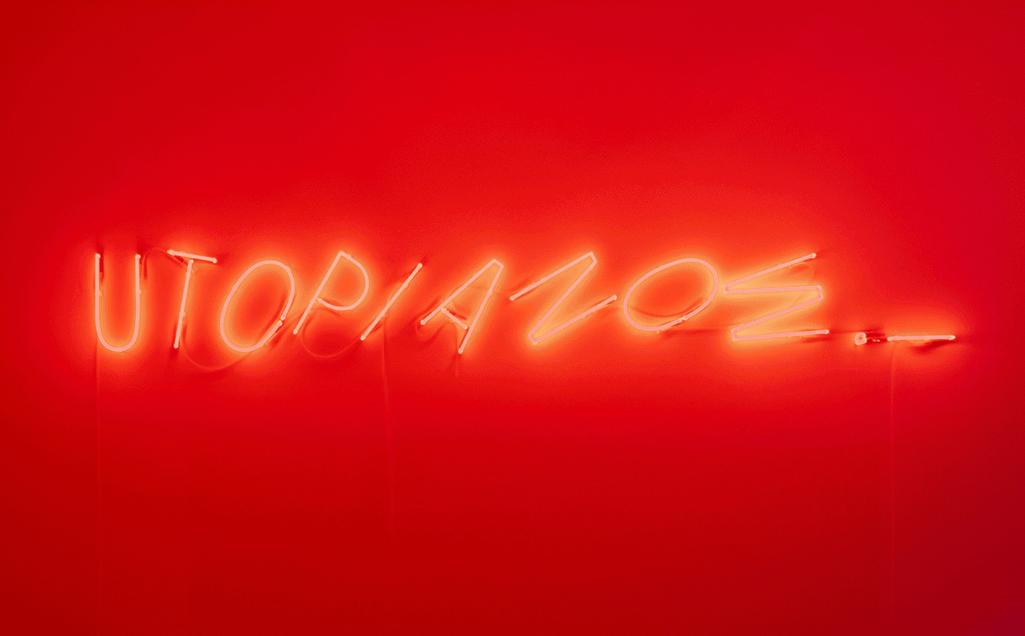 Un'insegna al neon rossa su un muro mostra la parola "UTOPIANOZ" in lettere maiuscole. Il bagliore dell'insegna crea una luce rossa ambientale, che proietta una tonalità calda attorno a sé.