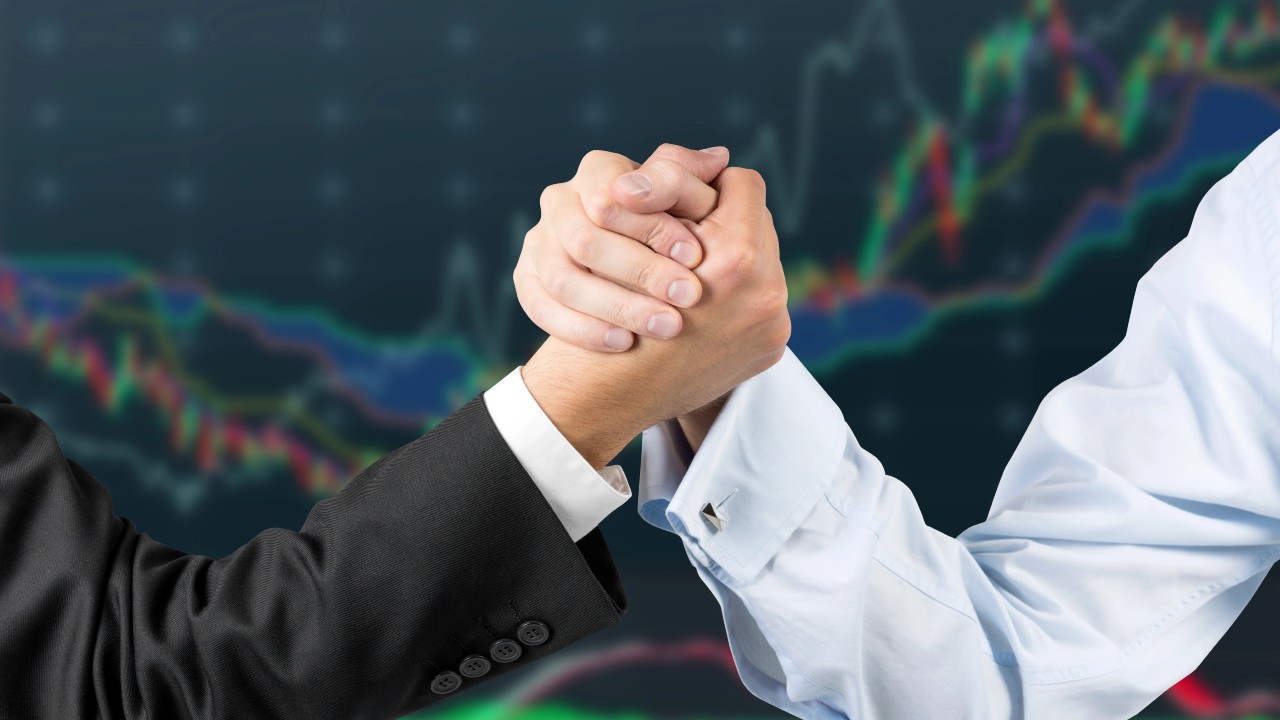 Braccio di ferro tra due persone, a simboleggiare il confronto tra Etf e gestione attiva. Sullo sfondo, linee colorate formano un grafico sfocato, che allude a dati di mercati finanziari o obbligazionari.