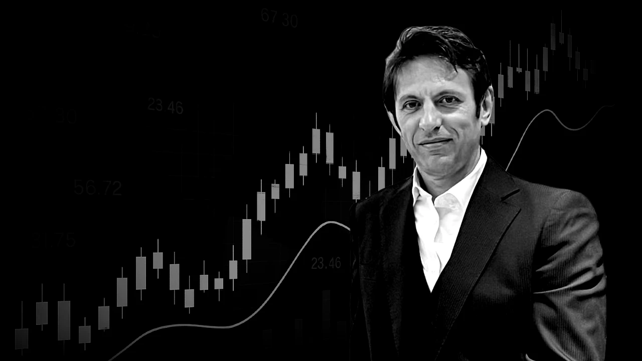 Un uomo in giacca e cravatta è in piedi davanti a uno sfondo scuro su cui è raffigurato un grafico a candele finanziarie e vari numeri, che suggeriscono un contesto finanziario o aziendale.