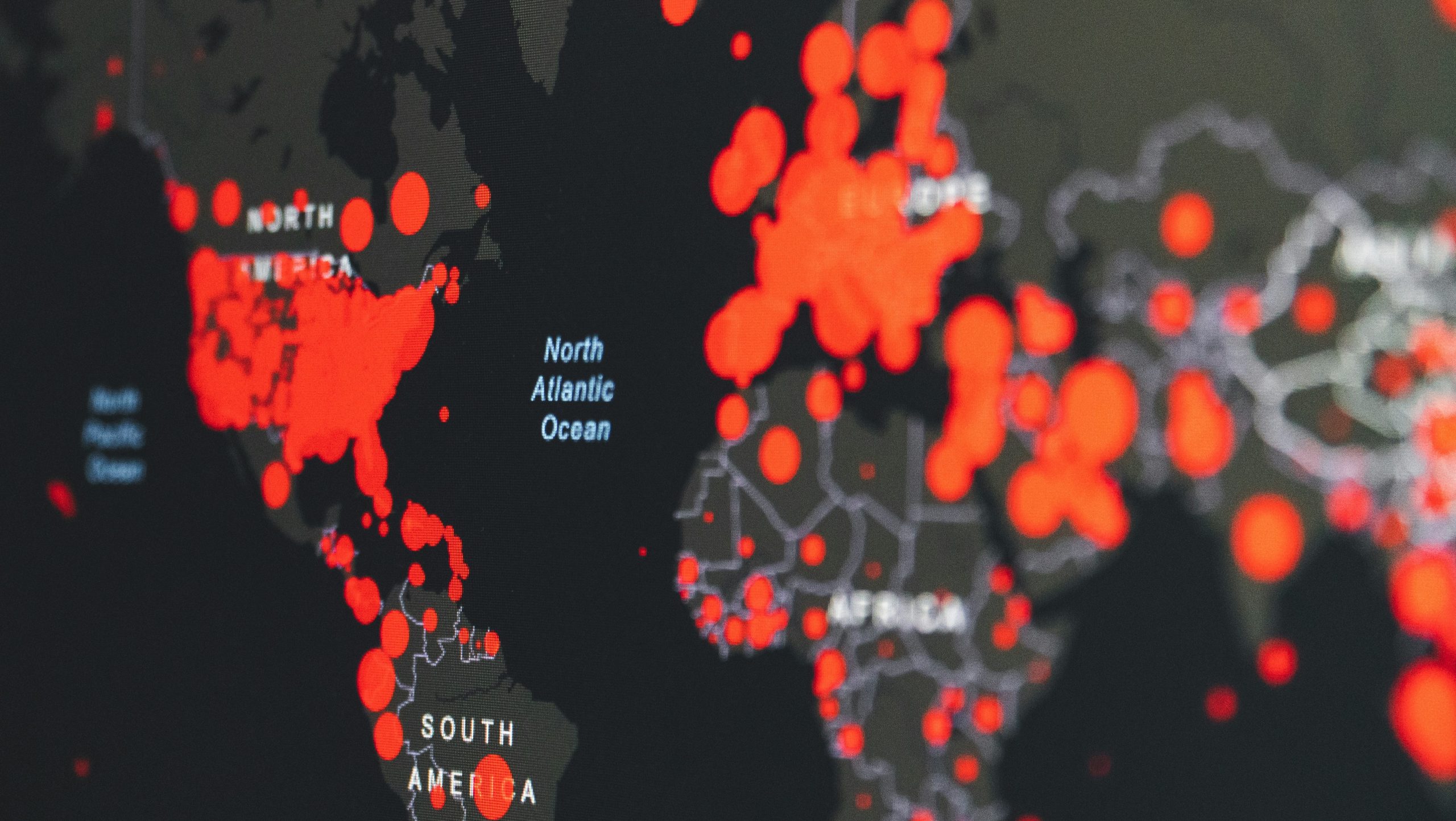 Una mappa del mondo mostra gruppi di punti rossi in Nord America, Europa, Sud America e Africa. Contrassegnata con continenti e oceani, illustra probabilmente gli effetti della diffusione globale nell'arco di cinque anni o l'impatto sulle economie in seguito al COVID.