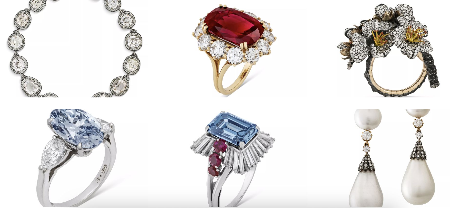 Una collezione di gioielli raffinati che comprende anelli con pietre preziose, una collana di diamanti, un anello floreale con accenti gialli, un anello con pietre preziose blu e lunghi orecchini pendenti di perle disposti su uno sfondo bianco.