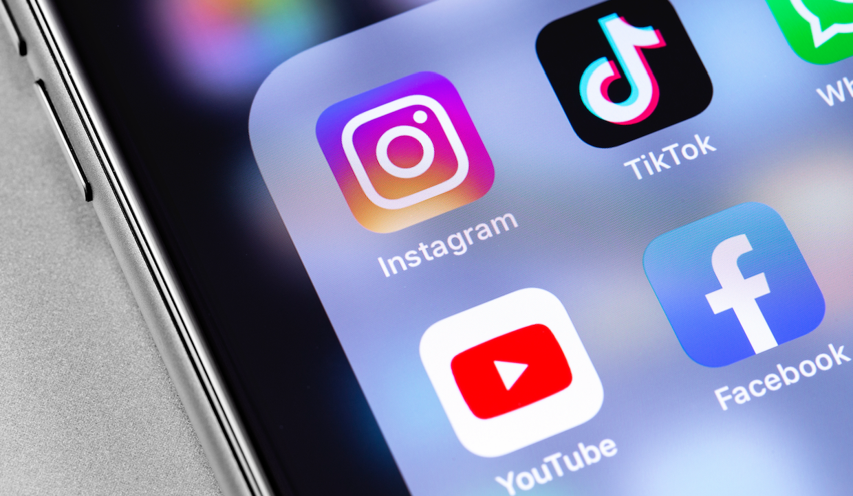 Lo schermo di uno smartphone mostra le icone delle app dei social media, tra cui Instagram, TikTok, Facebook e YouTube, su uno sfondo nero.