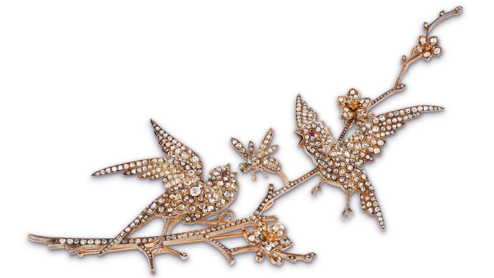 Spilla gioiello raffigurante due uccelli e fiori su un ramo, decorata con oro e cristalli scintillanti, su uno sfondo bianco.