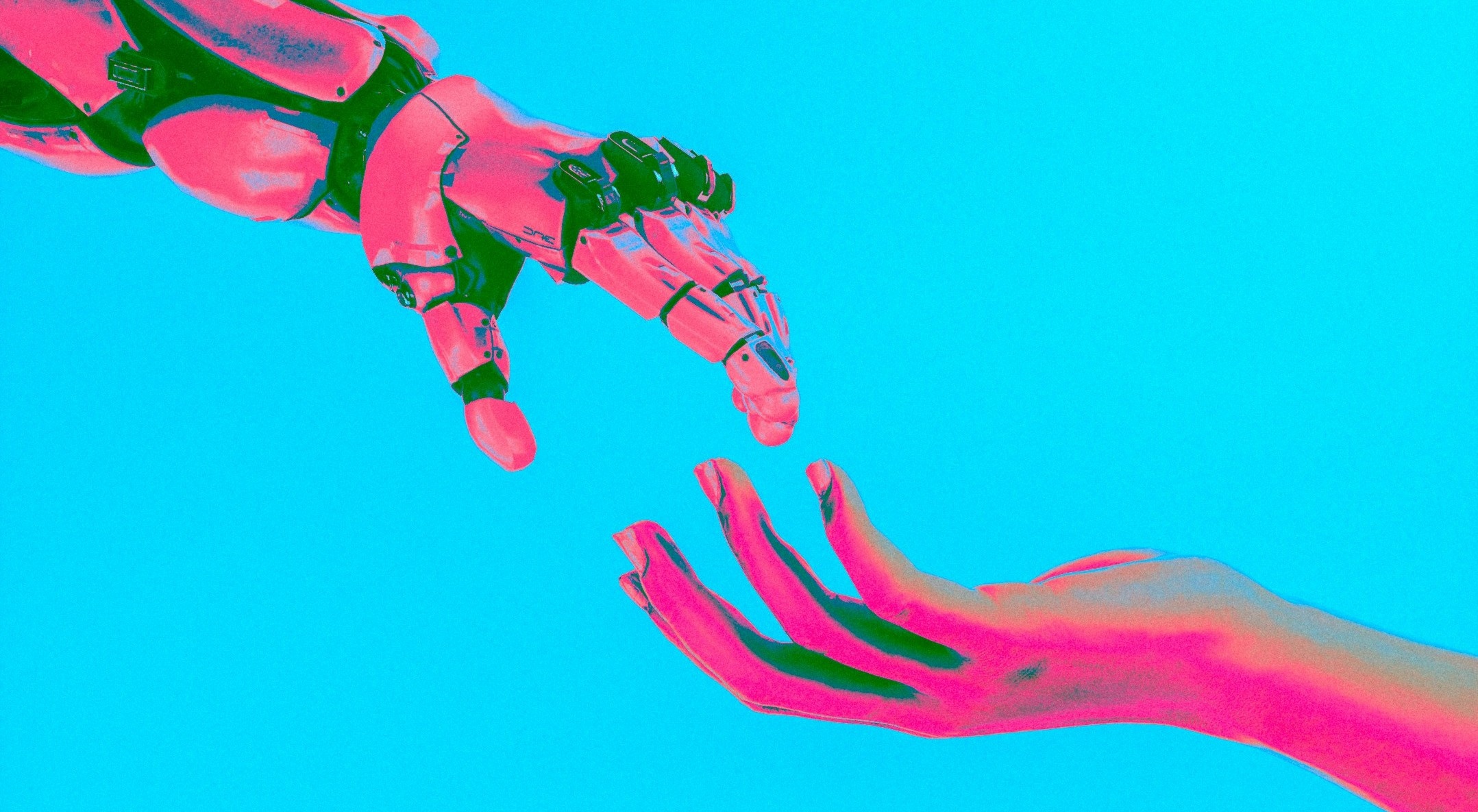 Una mano robotica si allunga per toccare una mano umana su uno sfondo blu brillante, evidenziando il legame tra tecnologia e umanità. L'immagine è stata filtrata con un filtro rosa e blu.