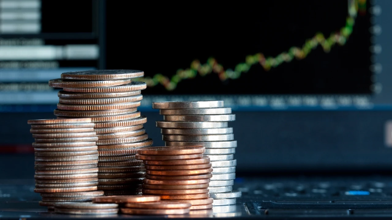 Pile di monete vengono posizionate davanti allo schermo di un computer su cui è visualizzato un grafico finanziario in crescita, a simboleggiare il potenziale di crescita del risparmio gestito.