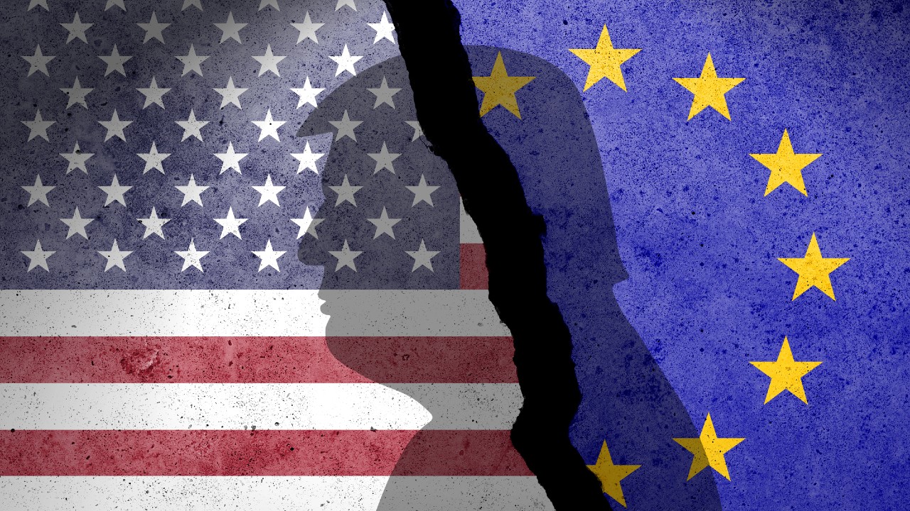 Un'immagine strappata mostra la bandiera degli Stati Uniti a sinistra e quella dell'Unione Europea a destra, divise da una silhouette spezzata: una metafora visiva del dazi e delle tensioni commerciali che minano l'unità.