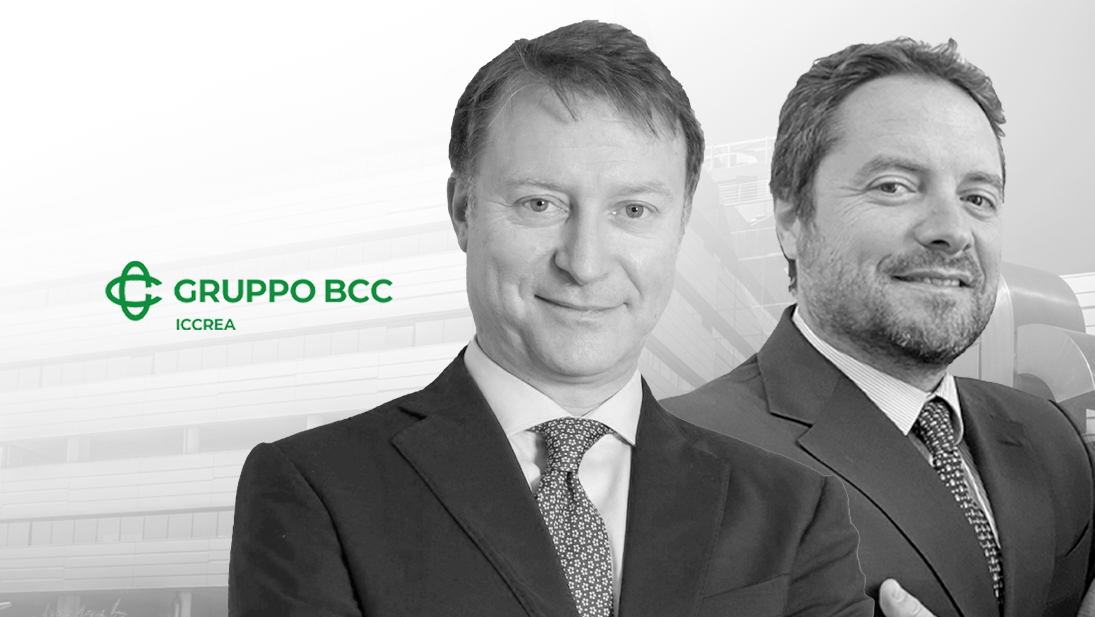Due uomini in giacca e cravatta sono in piedi davanti a uno sfondo sfocato di un edificio per uffici con il logo del Gruppo BCC ICCREA a sinistra, mentre discutono del futuro e approfondiscono le iniziative del 2025.