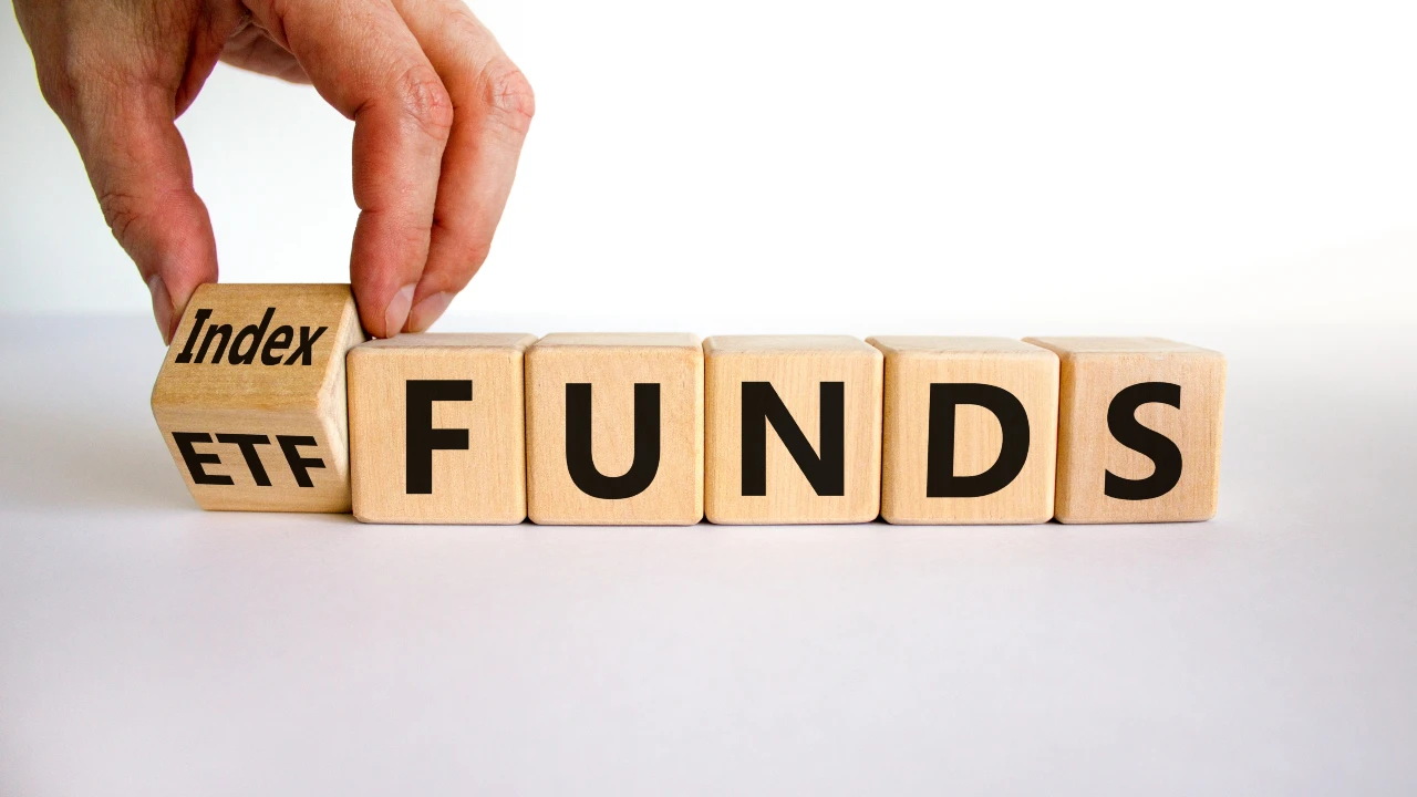 Una mano posiziona un blocco di legno etichettato "Index Etf" accanto ad altri che scrivono "funds" su una superficie bianca, in riferimento alla crescita di strategie investono in intelligenza artificiale (AI).