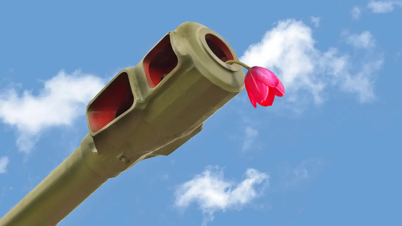 Un fiore rosso è posto nella canna del cannone di un carro armato verde, sullo sfondo di un cielo blu con alcune nuvole bianche.