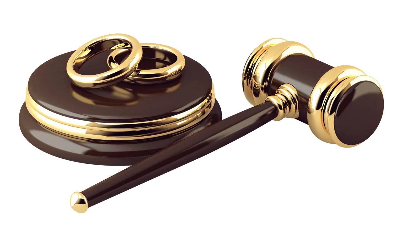 Accanto a due fedi nuziali d'oro, simbolo del matrimonio, c'è un martelletto, per raffigurare i procedimenti legali e gli accordi prematrimoniali.