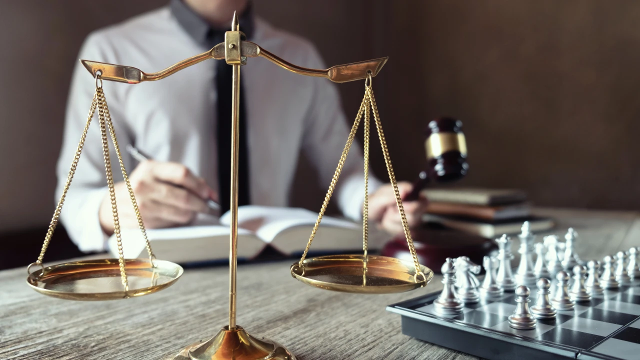 Una persona è seduta a una scrivania con un libro di diritto, un martelletto, una scacchiera e una bilancia d'oro in primo piano, evocando temi di giustizia e strategia che ricordano l'approccio di Elkann Agnelli alla legge e al processo decisionale.