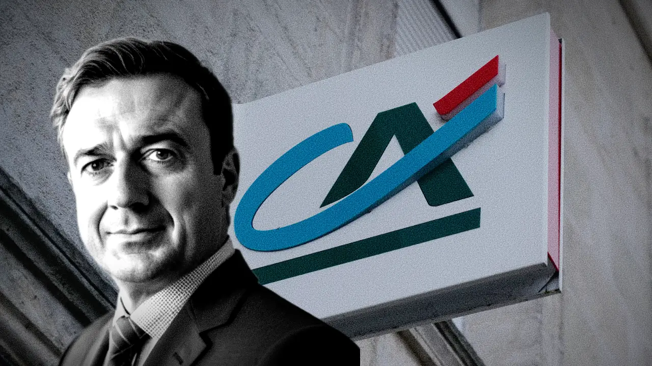 Un uomo in giacca e cravatta si trova di fronte a un edificio con il logo del Crédit Agricole, caratterizzato da una "CA" stilizzata verde e blu con un accento rosso su sfondo bianco.