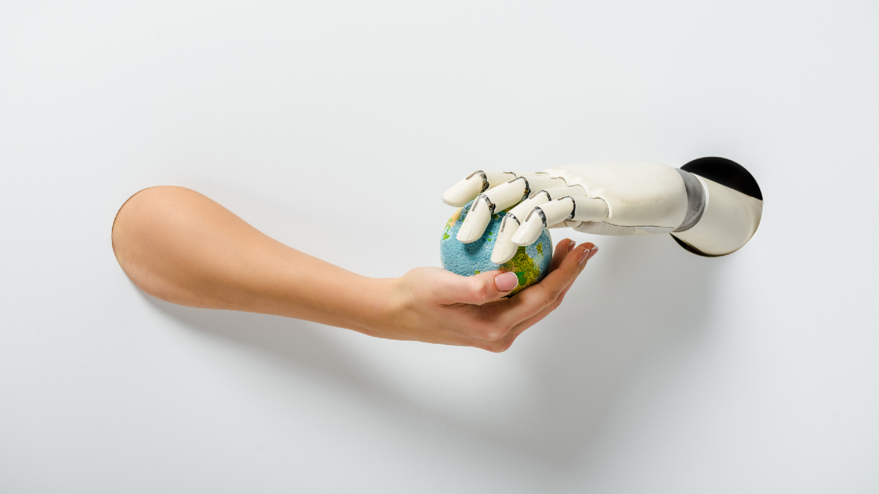 Un braccio umano e un braccio robotico si estendono attraverso dei fori in una parete bianca, con la mano robotica che passa un piccolo globo, simbolo delle azioni tra tecnologia e umanità, alla mano umana.