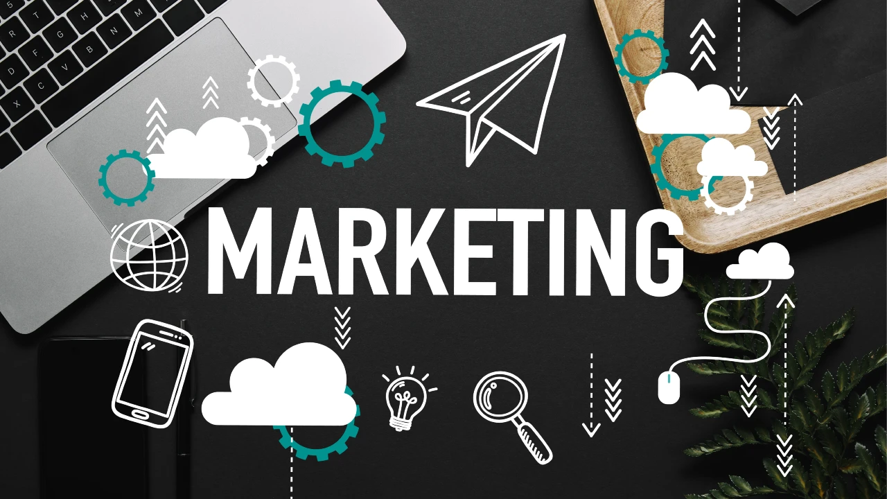 Un layout piatto di un computer portatile su una scrivania nera con la parola "MARKETING" in grassetto. Icone bianche (come una lampadina, un aereo di carta e una lente d'ingrandimento) sono sovrapposte per creare un'atmosfera aziendale creativa.