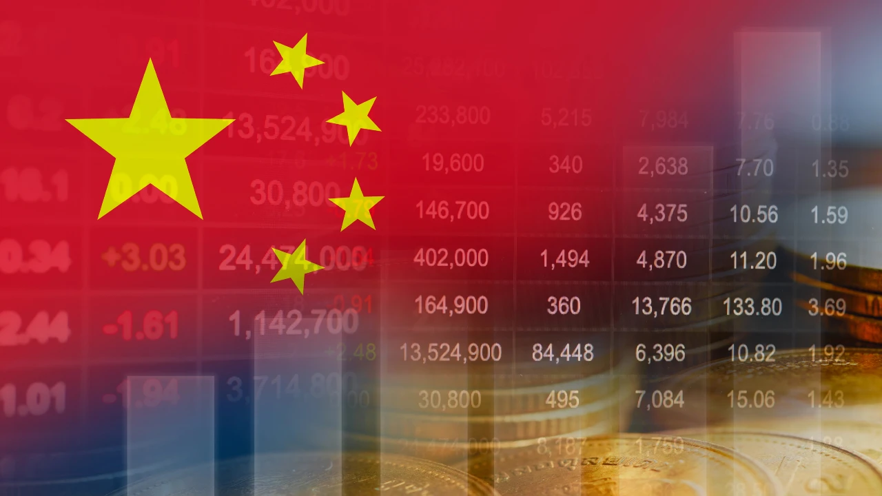 Bandiera della Cina sovrapposta a uno sfondo di dati finanziari, numeri di borsa e pile di monete d'oro, che simboleggiano l'economia e i mercati finanziari cinesi.