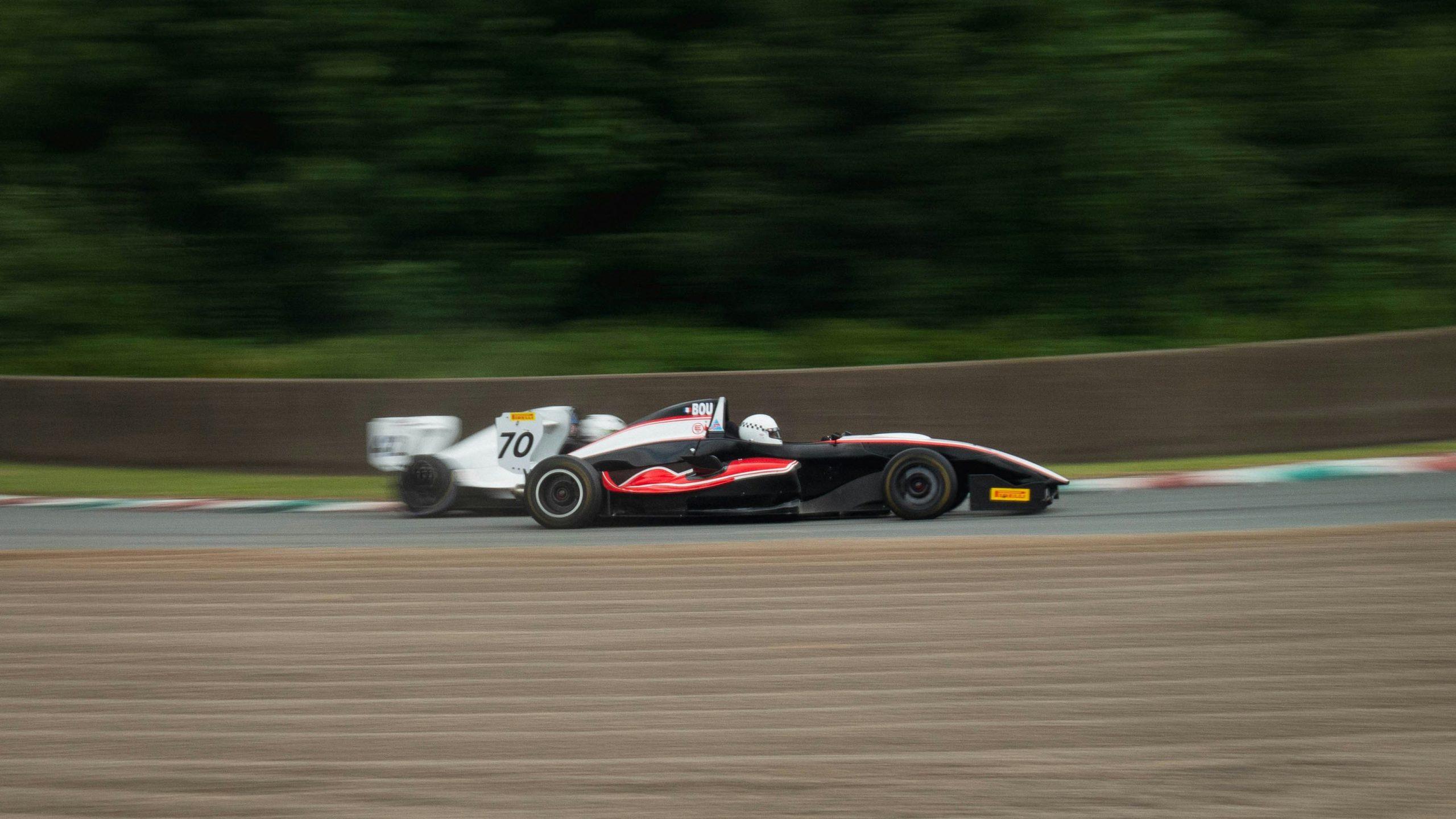 Due auto da corsa di formula sfrecciano su una pista, con l'auto numero 70 in bianco che insegue un rivale nero e rosso. Lo sfondo sfocato enfatizza il loro movimento veloce, proprio come le banche europee che investono con decisione in mercati competitivi.