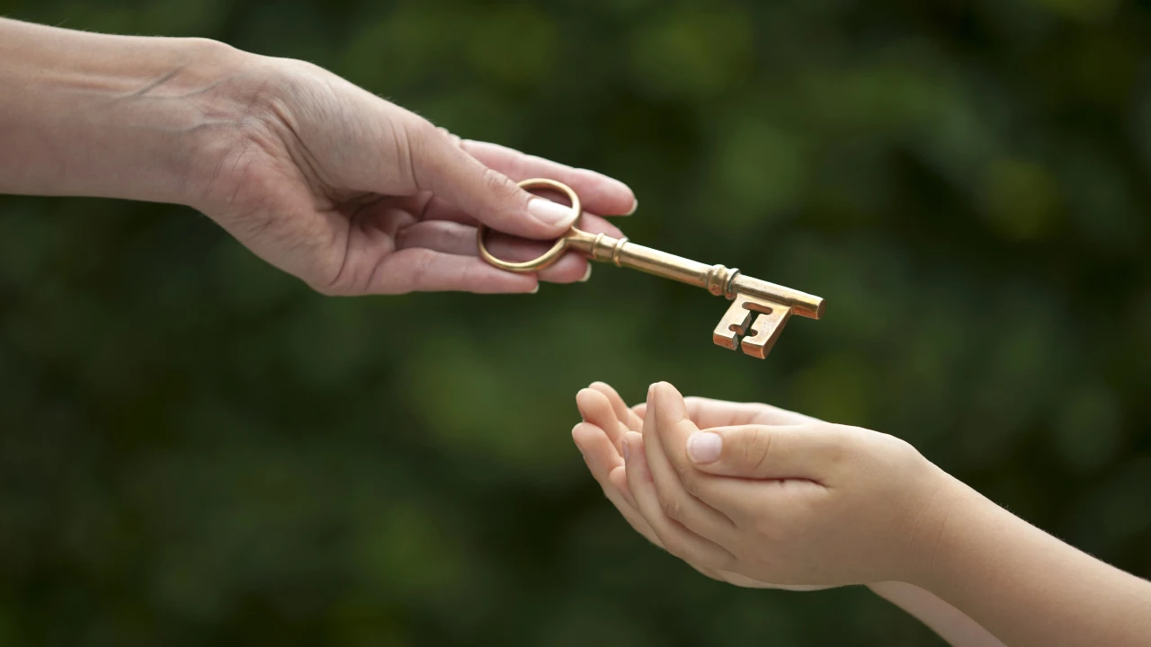 Primo piano di una mano adulta che passa una chiave d'epoca in ottone nelle mani aperte di un bambino, simbolo del passaggio generazionale.