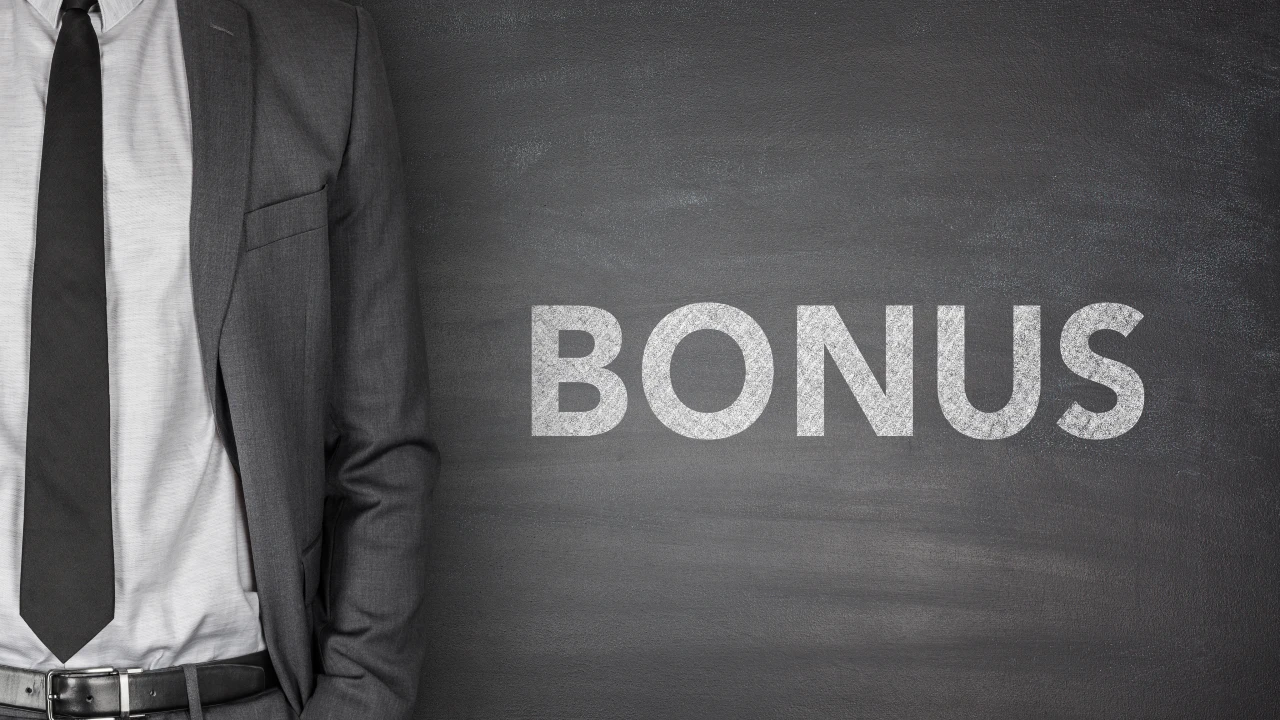 Una persona in abito da lavoro grigio si trova accanto a una lavagna con la parola "BONUS" scritta a grandi lettere bianche, evidenziando il concetto di premio addizionale. Il riferimento va all'articolo Addizionale Irpef 10%: stop su bonus per holding e family office.